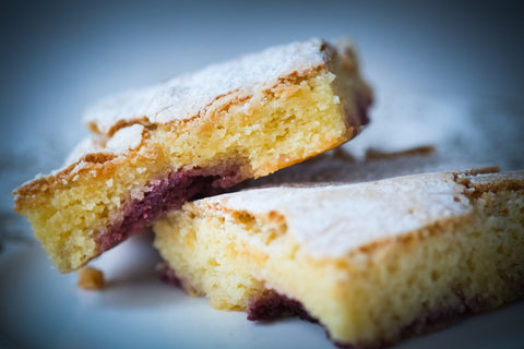 Two slices of cake with a cherry filling on a white plate against a blue background