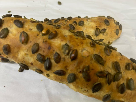 Finger roll of bread with pumpkin seeds on a white surface