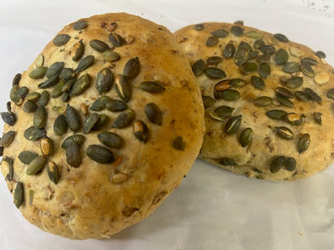 Two round bread rolls with pumpkin seeds on a white background
